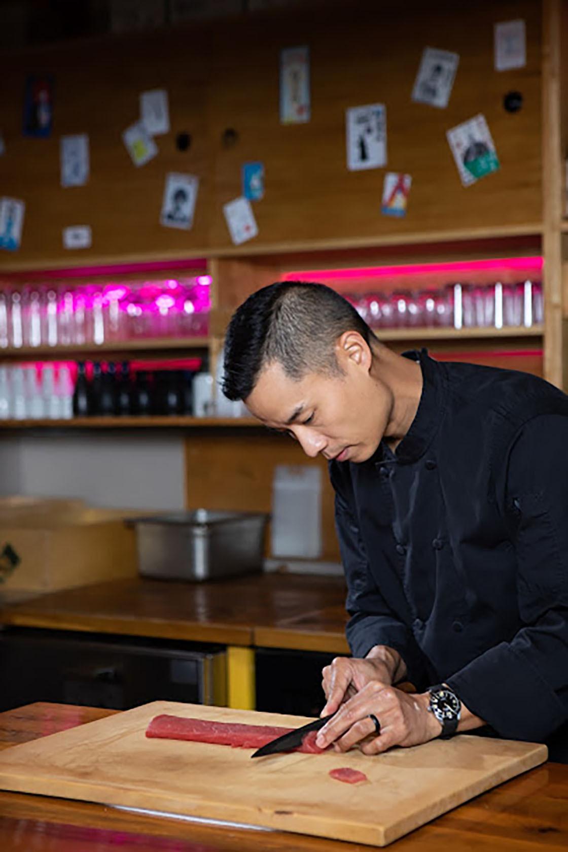 Chef Jay Huang slicing fish at his restaurant