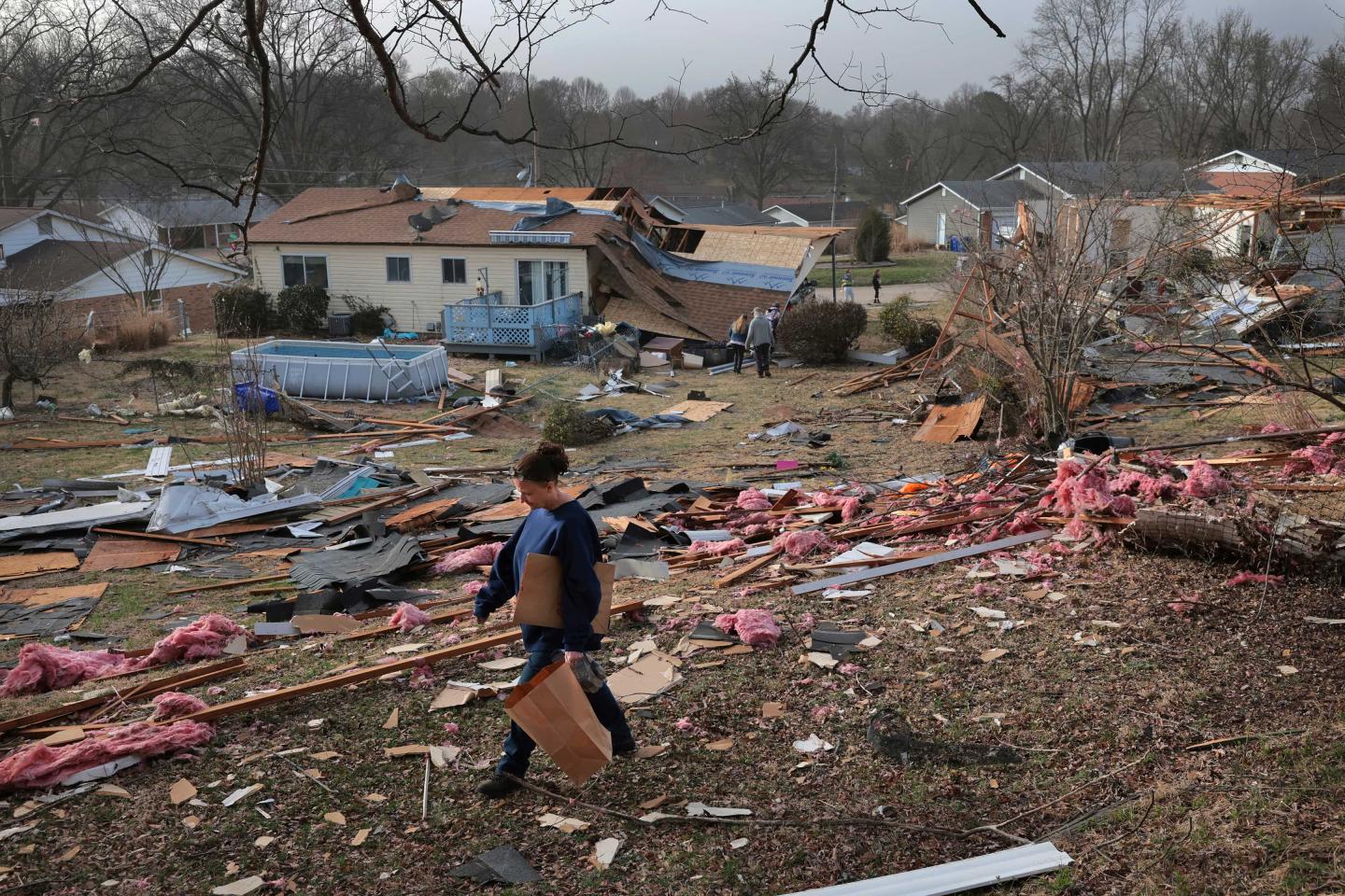 A person walking through debris after a tornado