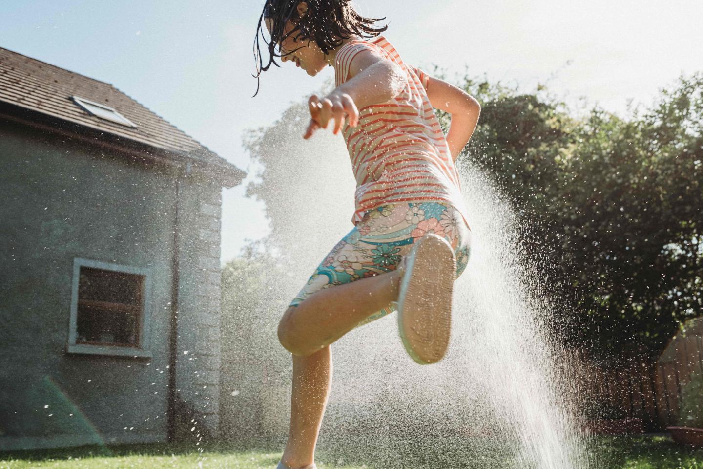 A child running through a sprinkler outside