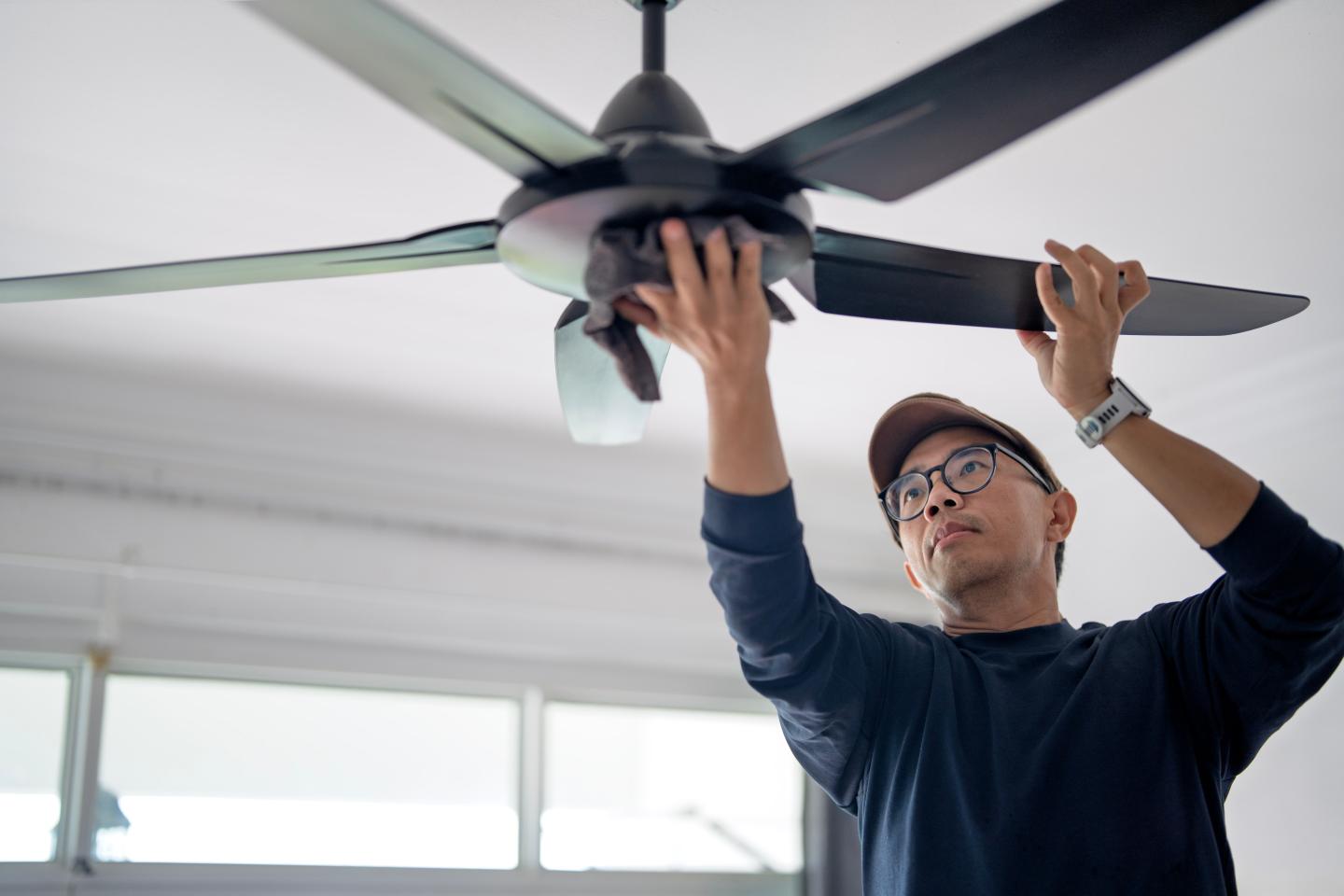 A man installing a ceiling fan