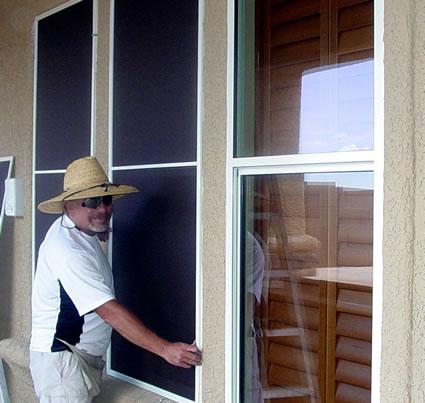 A man installing solar screens on windows