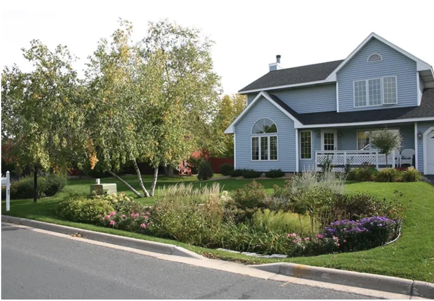 A house with a beautiful rain garden of flowers outside 