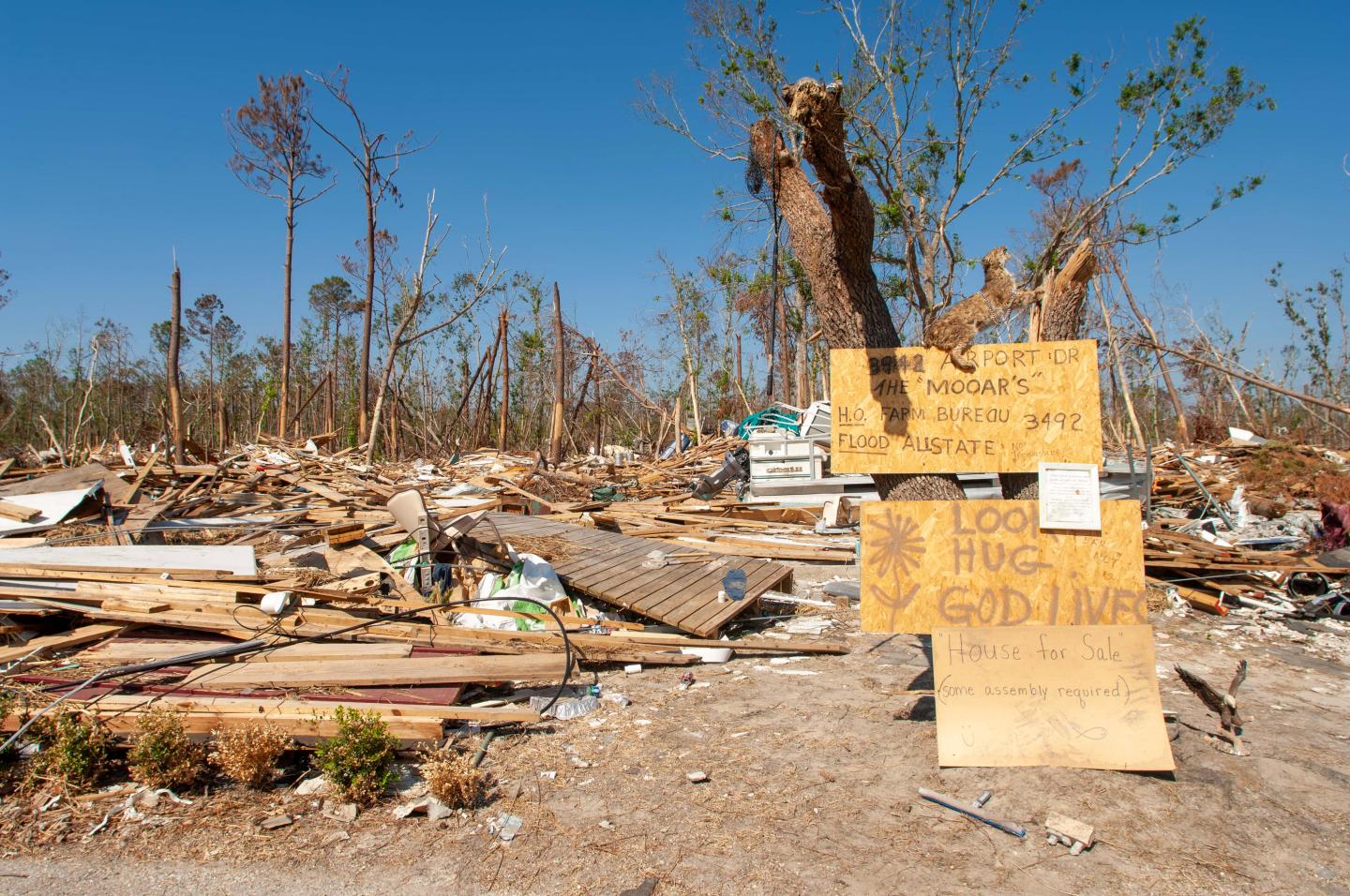 House debris litters Diamondhead, Mississippi, with a sign that says "House for sale, some assembly required"