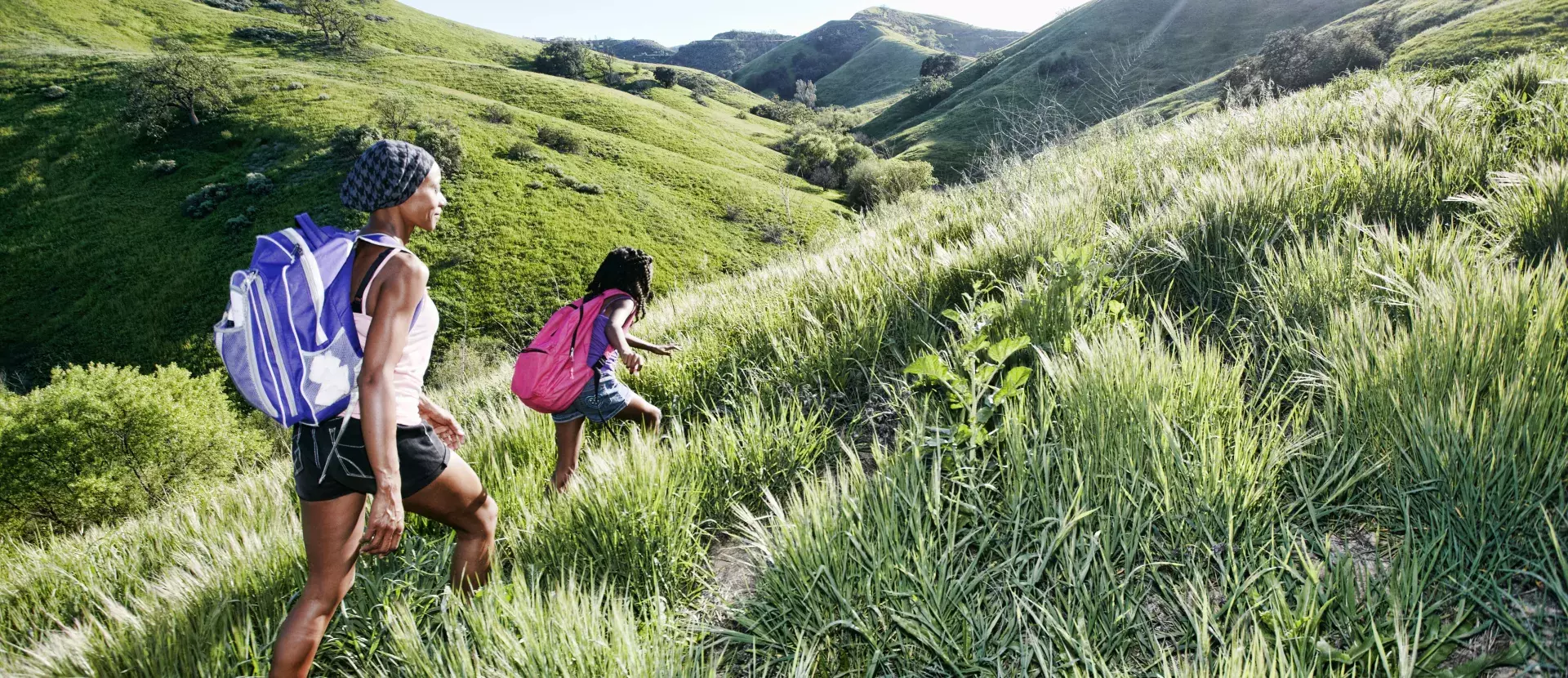 Two people hiking across some hilly green fields