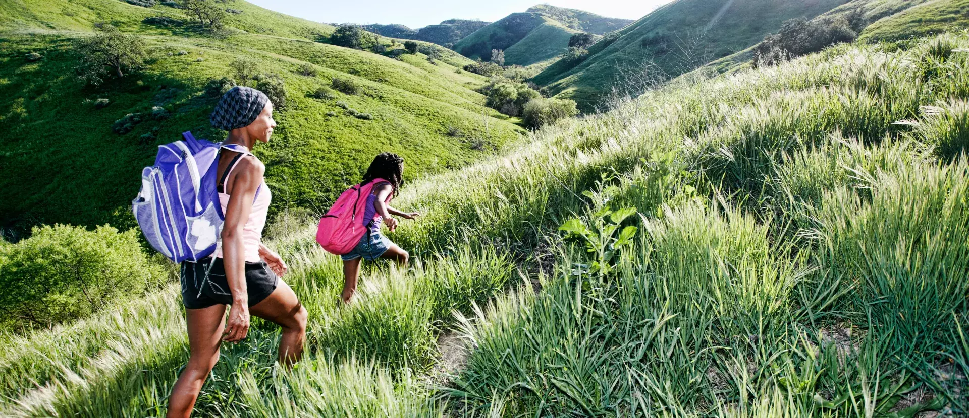 Two people hiking across some hilly green fields