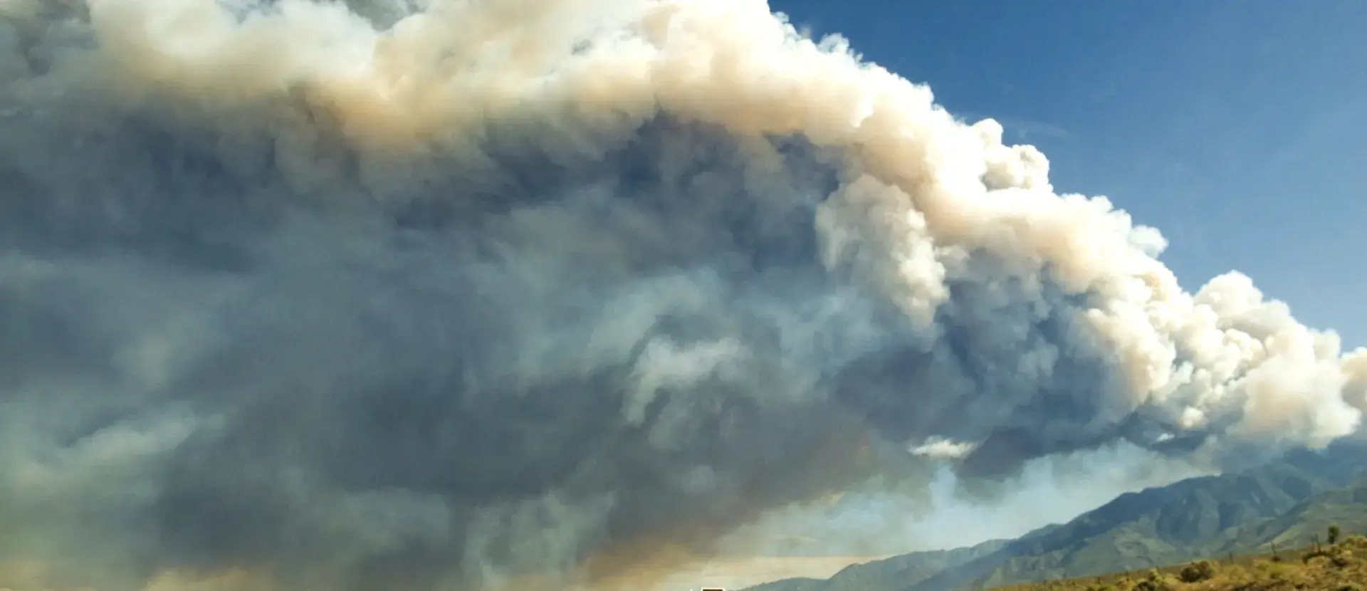 An RV driving down the road with white smoke covering the horizon