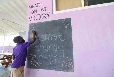 A student at a chalkboard writes "Positive energy only"