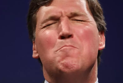 Closeup of Tucker Carlson's face, seemingly in pain