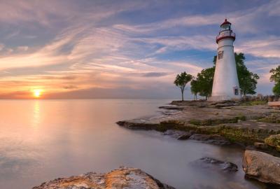 A lighthouse on the banks of Lake Eerie while the sun rises in the distance — the sun could be setting, but it just gives off rising vibes, you know what I mean?