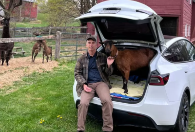 Robert McKeon sits inside his Tesla with one of his goats