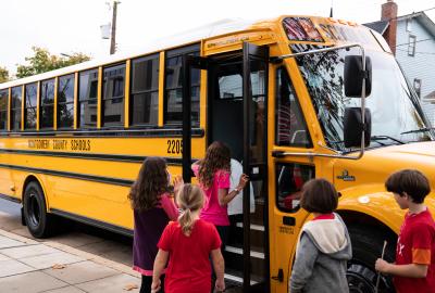 Kids file onto a yellow school bus