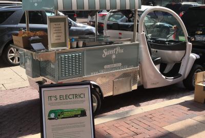 An electric ice cream truck sits parked on a busy city street