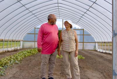 Fifth-generation farmers Millard and Connie Locklear stand in a plastic tunnel similar to the one in which they grow their tomatoes