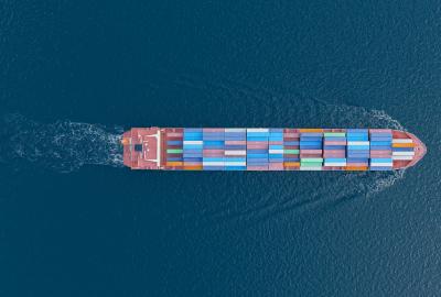 An overhead shot of a shipping container laden boat traveling in open water
