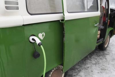 An old van that has been converted into an electric vehicle with a charging cable connected
