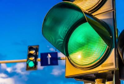 Two traffic lights, one in the foreground, one in the back, both green