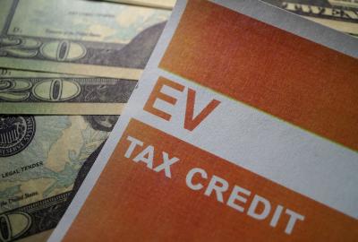A pamphlet with EV tax credit written on it and cash behind it