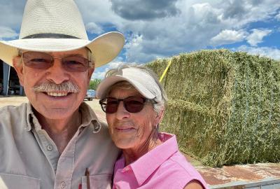 Don and Jane Schreiber standing in front of a large bail of hay