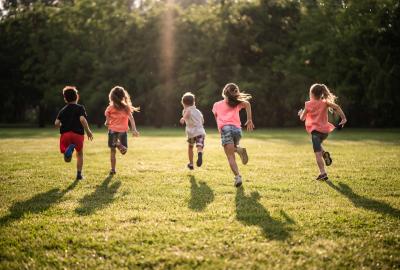 A bunch of kids running across a grassy field