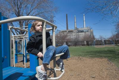 A four-year-old plays on a park next to a coal-fired power plant