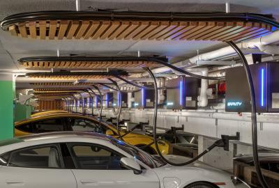 A row of electric cars plugged into chargers overhead