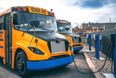 A row of electric school buses plugged in