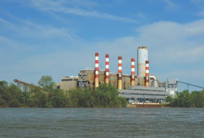 A Duke Energy facility with red and white smokestacks along a river