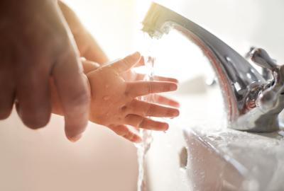 A baby's hands being washed in a sink