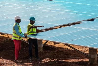 Two workers overlooking large solar panels