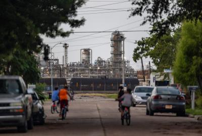 Kids riding bikes down a street with a power plant in the background