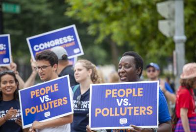 Protestors holding "People vs polluters" signs