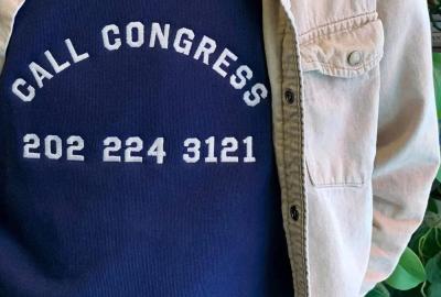 A person wearing a shirt that says "call congress 202-224-3121" on it