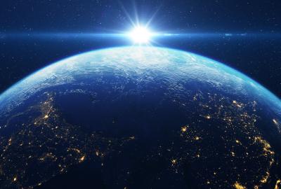 The Earth from space with the sun in the distance glowing like a bright future