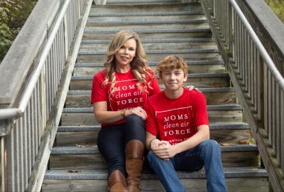 A mother and son sitting on steps wearing "Moms Clean Air Force" shirts