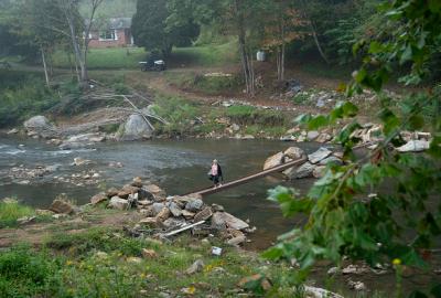 Woman walking across makeshift narrow bridge