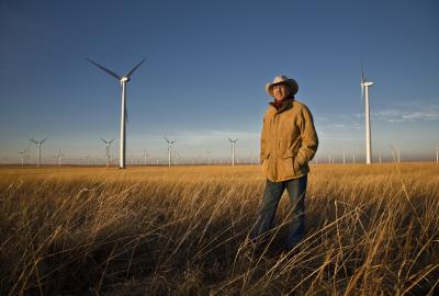 Pete Ferrell standing in grass field in front of wind turbines
