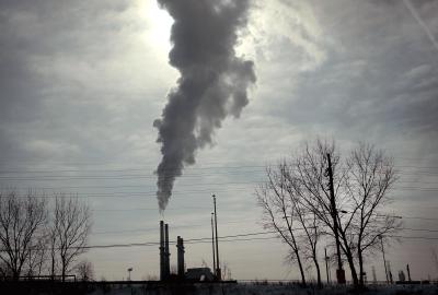 A plume of smoke blotting out the sun coming out of a coal power plant