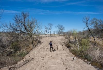 A man surveys water flow from a dusty road