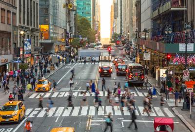 People crossing at a crosswalk in a bit of time lapse blur on a sunny New York City street