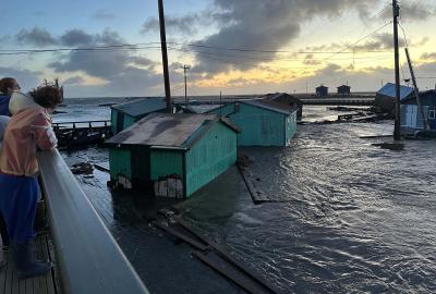 People looking off a bridge at the flooded town of Kipnuk
