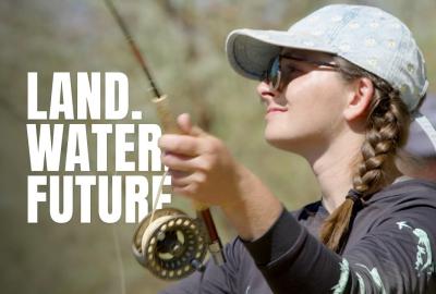 A woman holding a fishing rod with the text "Land. Water. Future." imposed on the screen
