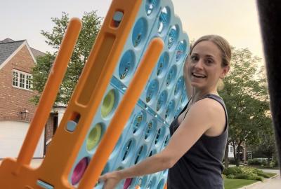 Claudia von Mallinckrodt holding a large tic tac toe board she pulled from someone's trash