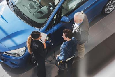 An overhead shot of three people standing near a car in a showroom