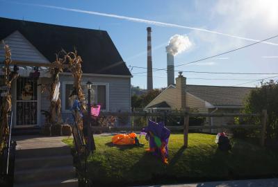 A residential home with two towering smokestacks in the background