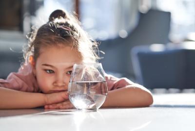 A small child looking at a glass of water