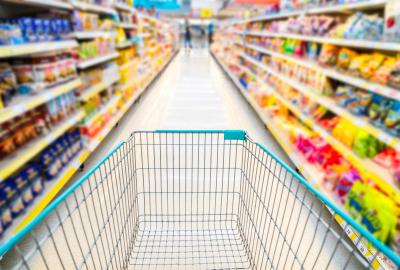 A shopping cart going down a colorful aisle at the grocery store