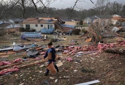 A person walking through debris after a tornado