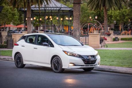 Nissan Leaf electric car driving in front of a city park with bandstand and palm trees