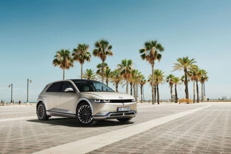 A silver Hyundai Ioniq parked on a concrete parking lot. Shot from low on the ground, with palm trees in the background against a blue sky