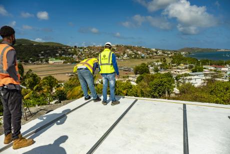 Three people working on a roof overlooking Culebra, Puerto Rico